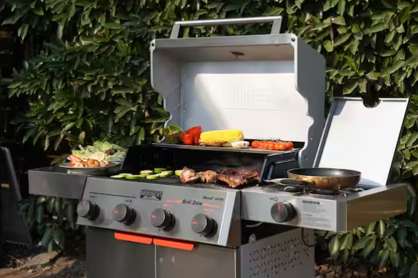 Asador de gas Monument Grills de 4 quemadores, tapa abierta y parrilla con comida