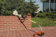 Desbrozadora STIHL con tubo plateado y protector naranja para desbroce en jardín