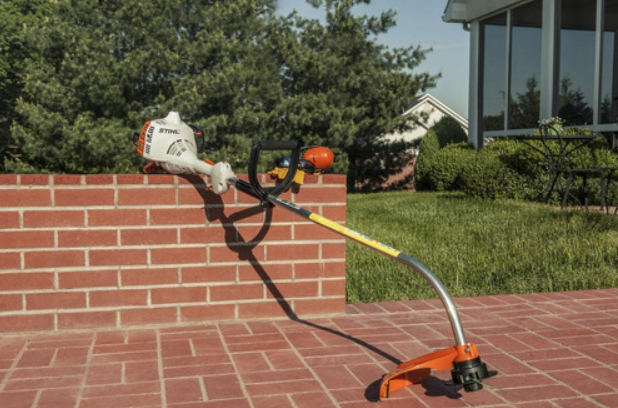 Desbrozadora STIHL con tubo plateado y protector naranja para desbroce en jardín